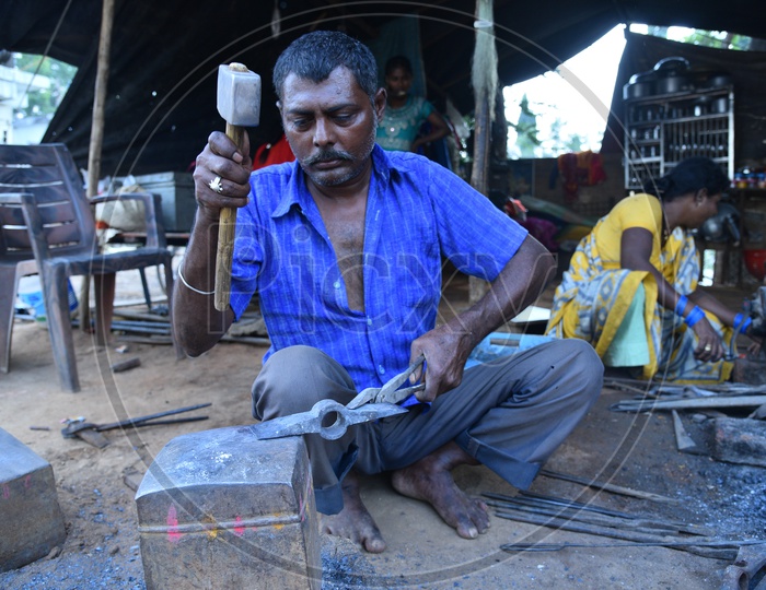 A Blacksmith Shaping the Iron Piece using Hammer