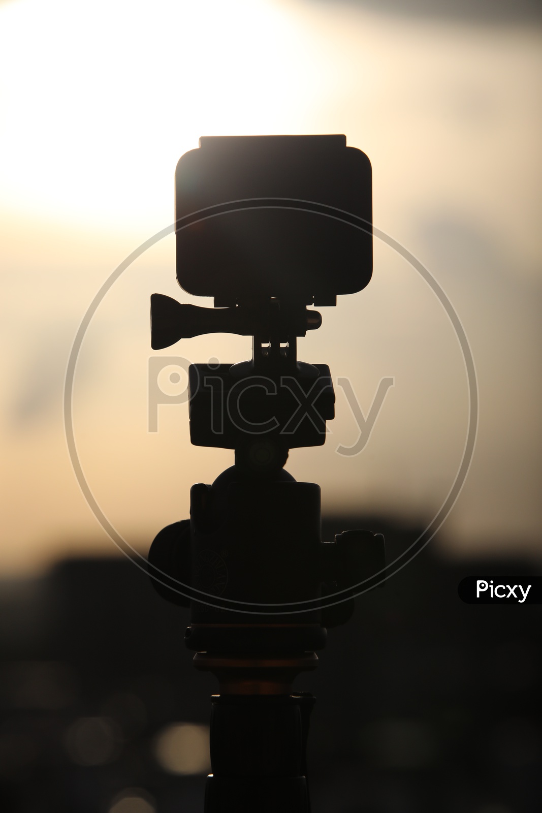 Silhouette Of a Go Pro Action Camera  Mounted To a Tripod To Shoot A City Scape
