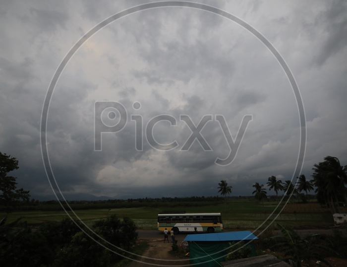 Heavy Trucks Parked On Road At a Rural Village With Cloudy Sky As Background