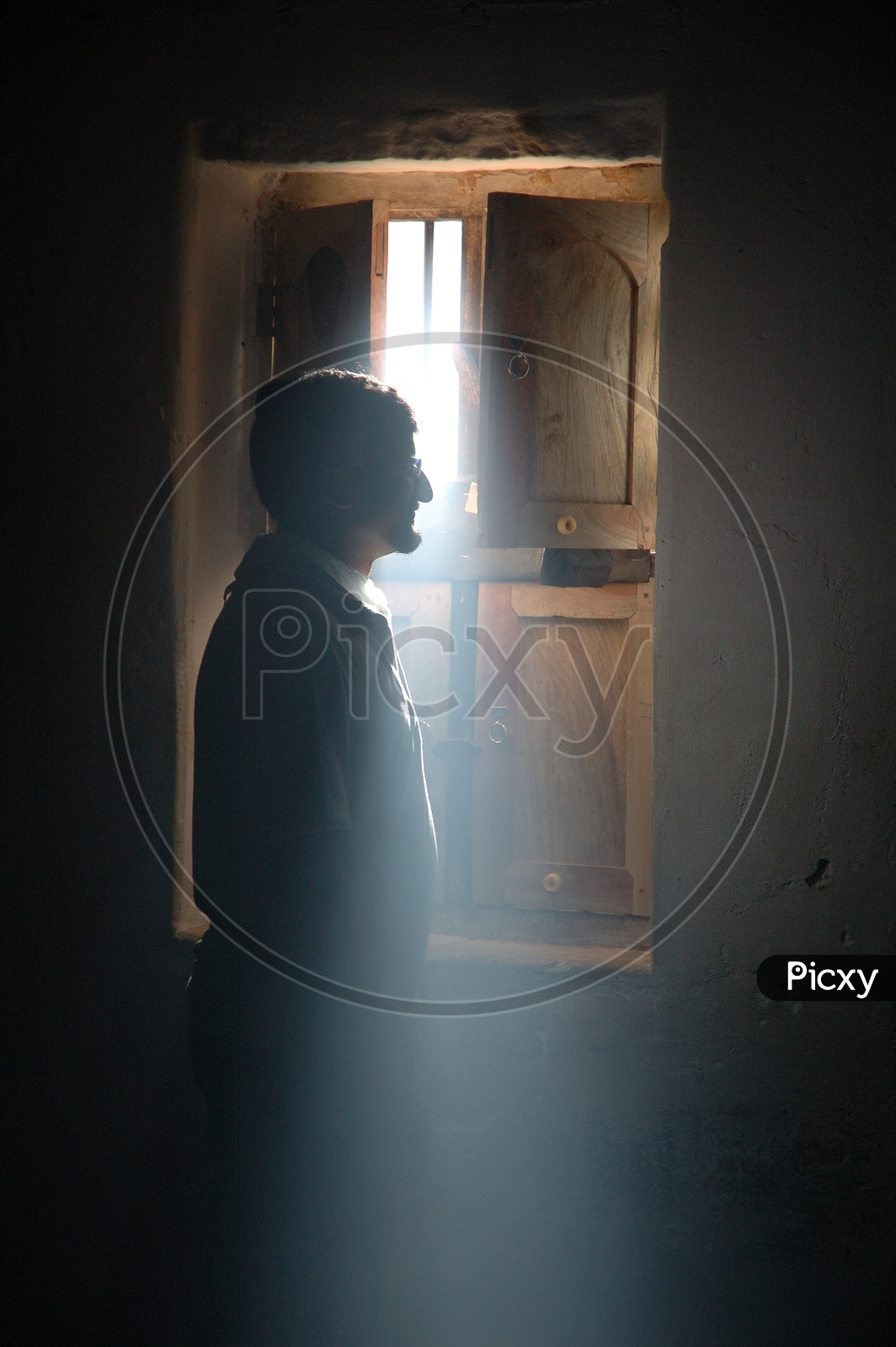 Silhouette Of a Man Standing At a Window With Light Falling On Him