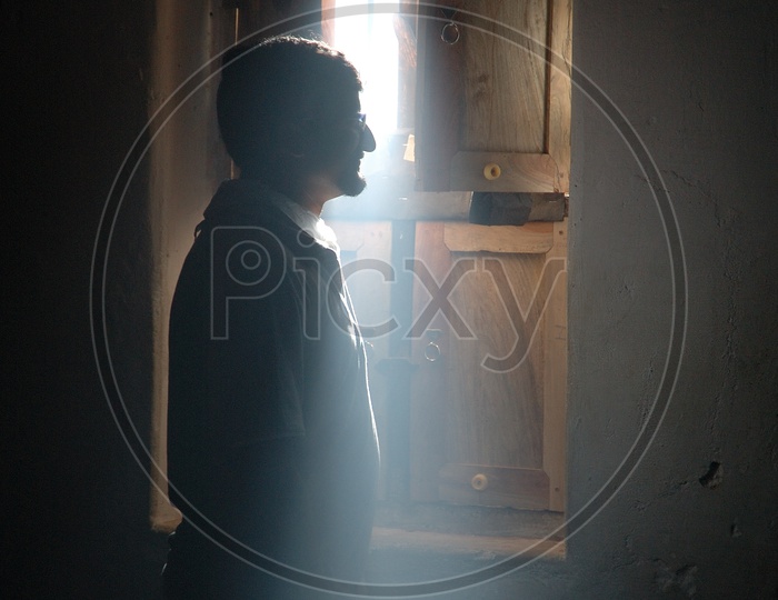 Silhouette Of a Man Standing At a Window With Light Falling On Him