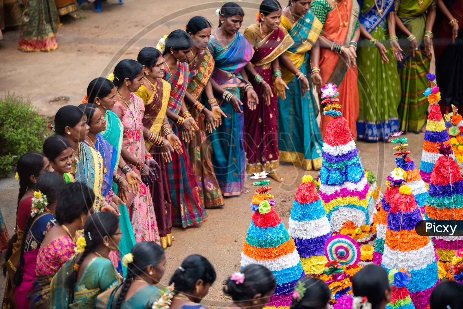 women dance in front of Bathukamma, a floral decoration made of medicinal flowers