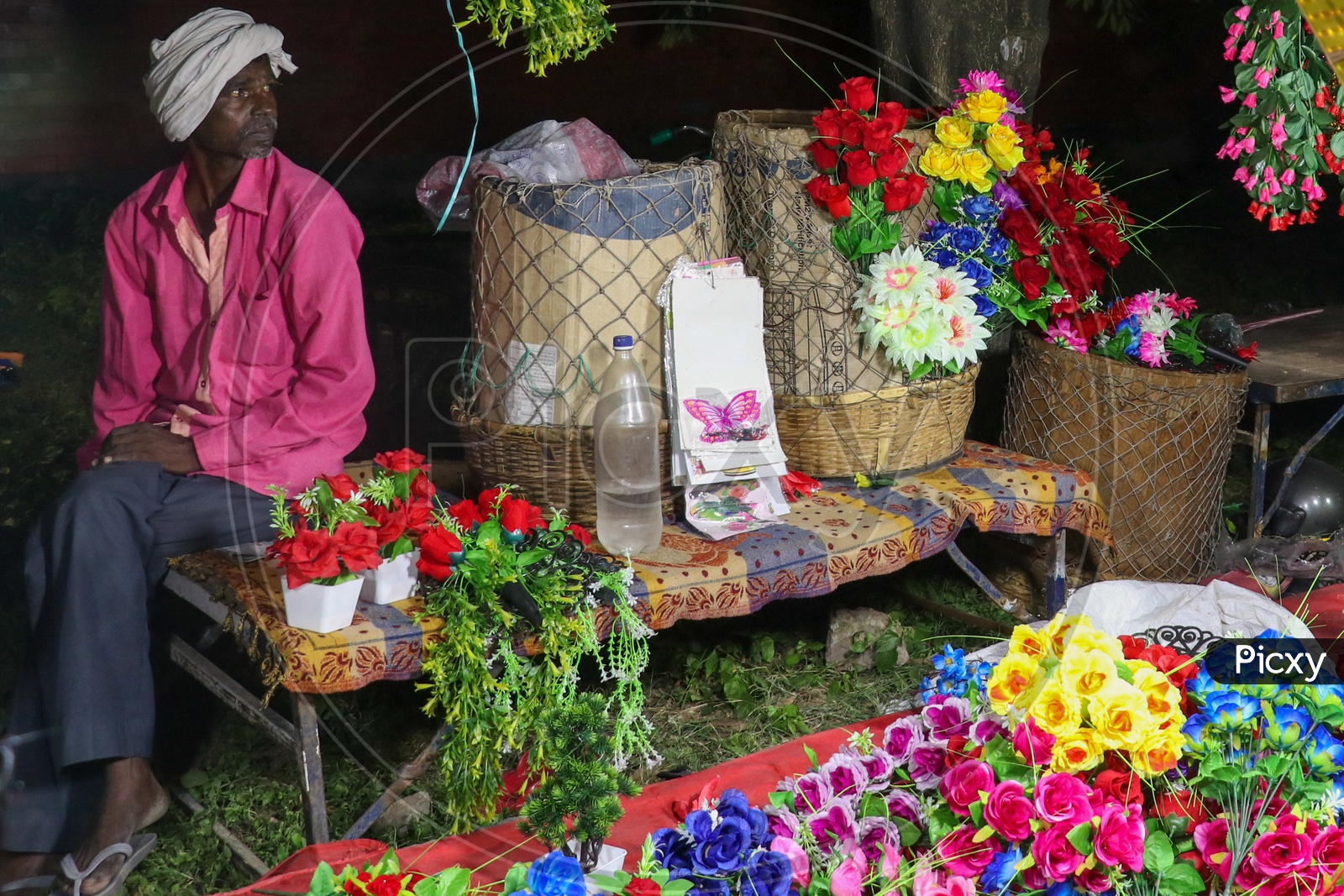 An old man selling artificial flowers on a roadside