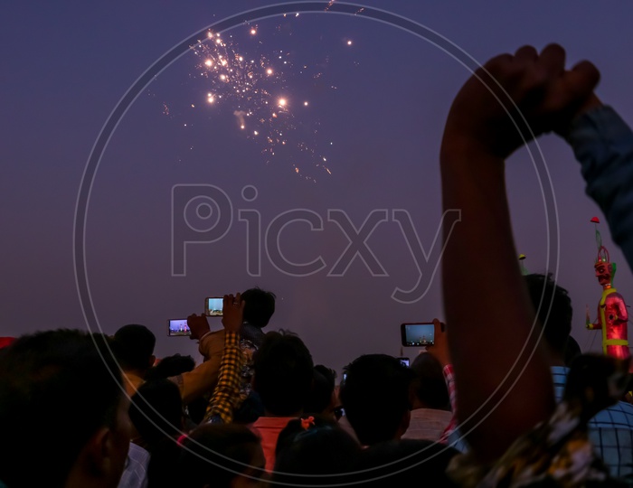Crowd taking photos and videos of fire crackers near effigies of Ravan during Dussehra celebrations, 2019.