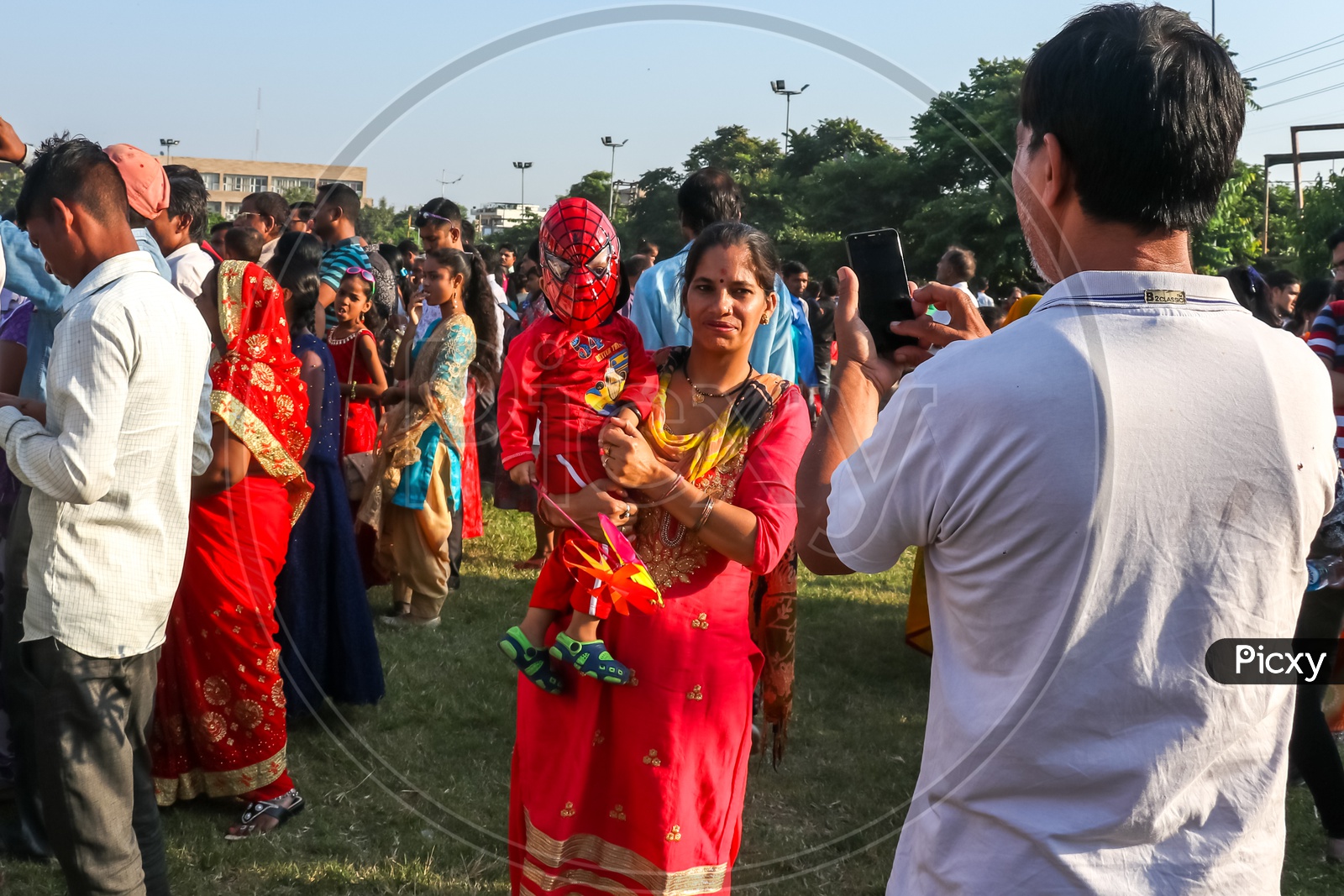 A man clicking a photo of a boy along with his mother amongst crowd