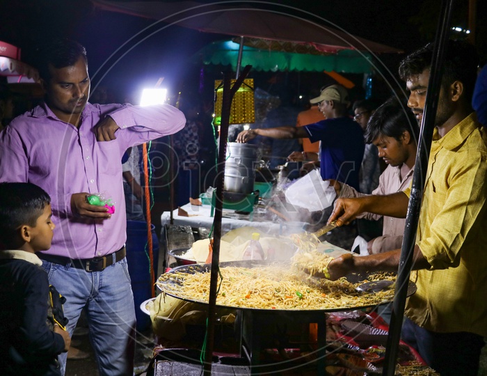 People buying street food noodles in a night market