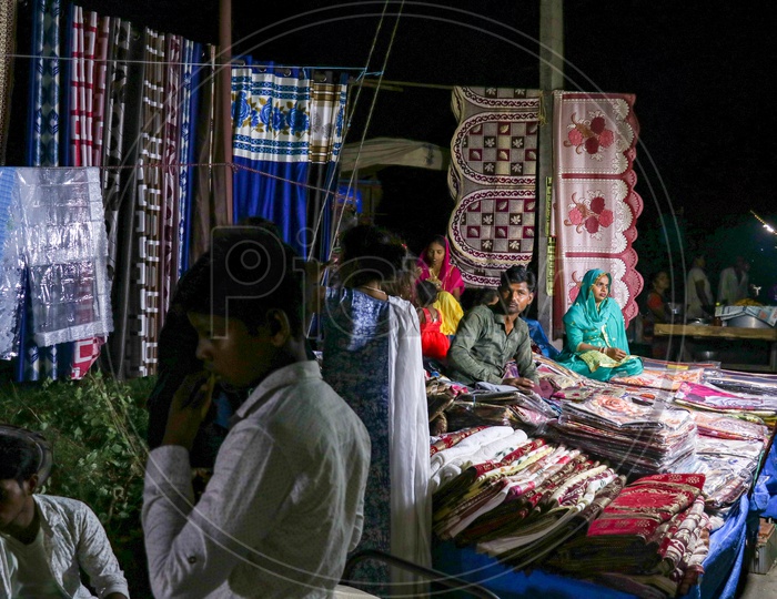 A street vendor selling curtains and bedsheets in a market