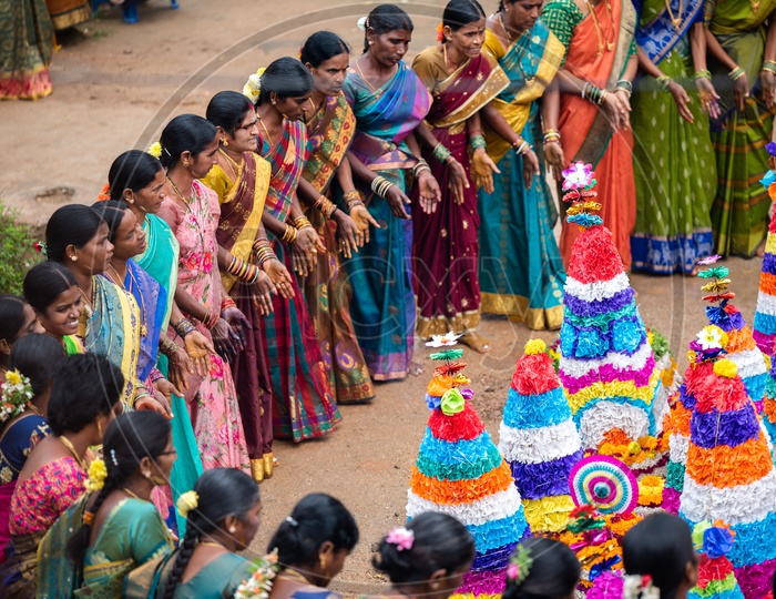 women dance in front of Bathukamma, a floral decoration made of medicinal flowers