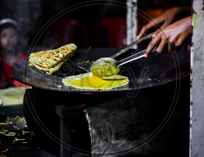 Making Of Egg Roll On A Hot Frying Pan With Oil And Paratha And Salad