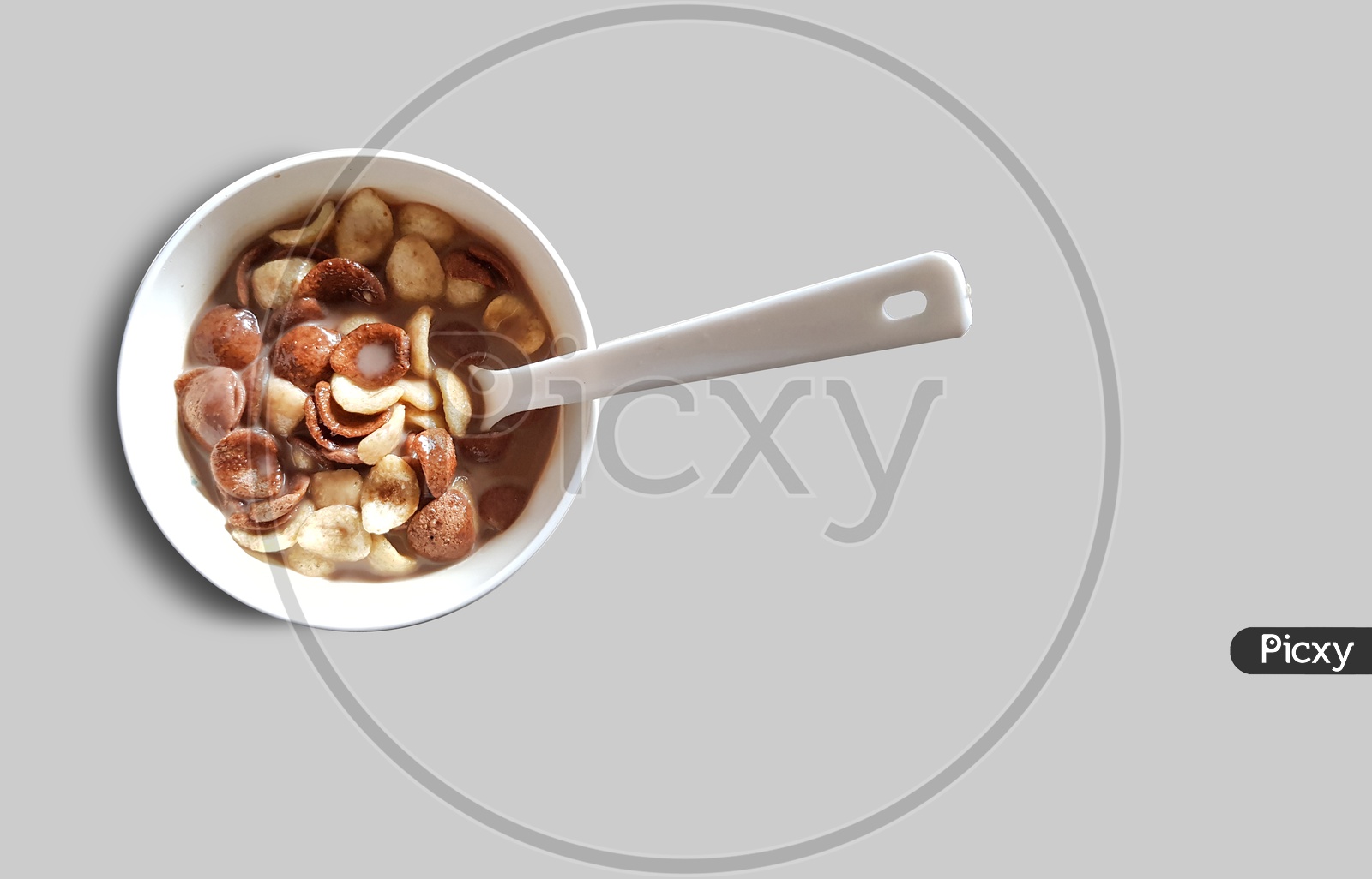 Vanilla And Chocolate Cornflakes Dipped In Chocolate Milk In A White Bowl In Light Background With Spoon