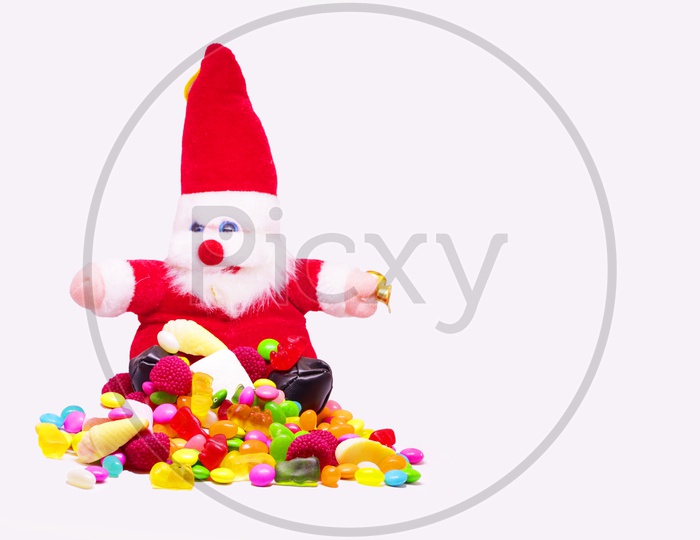 Santa Clause And Multi Colored candy In White Background With Space For Text, Christmas Celebrations