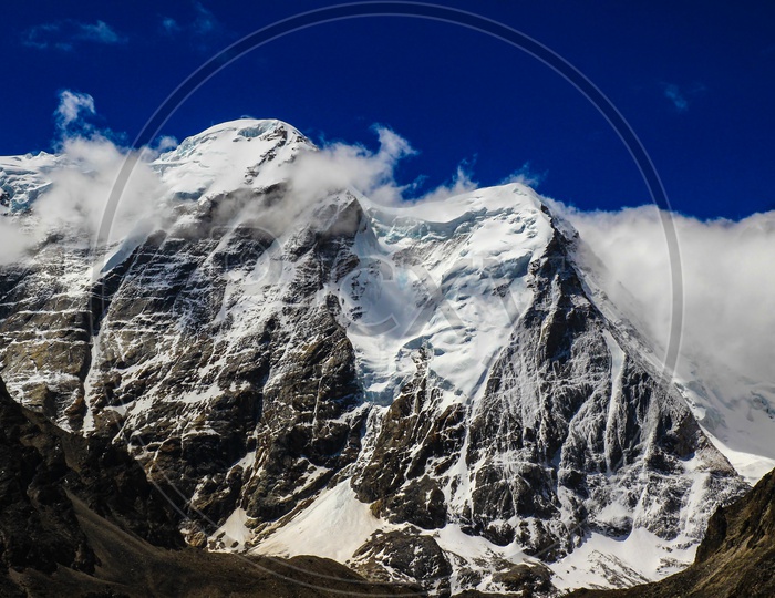 Landscape Of Deep Blue Sky And Ice Capped Peaks Of Himalayan Mountains With White Clouds During Day Time
