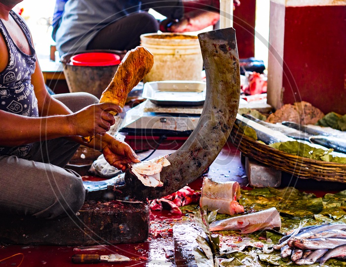Fisherman Cutting Fish On A Standing Blade Boti With The Help Of A Wooden Stump In Indian Fish Market At Kolkata