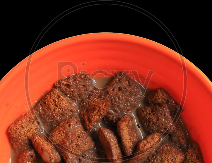 Close Up Photo Of Chocolate Cornflakes Dipped In Chocolate Milk In Black Background