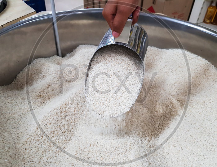 Hand Pouring Raw Uncooked Heap Of Rice With Measuring Mug Dispensing Container At Supermarket For Sale