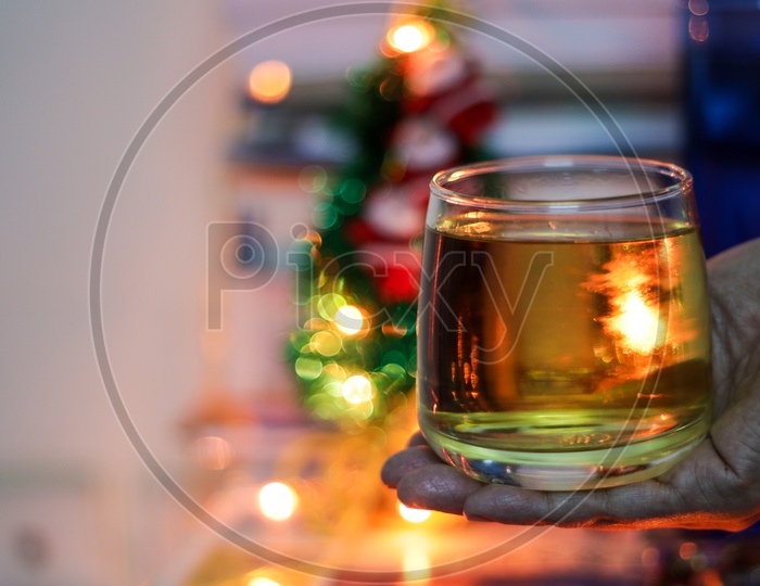A Glass Of Alcohol Rum Held In Hand With Background Blurred Bokeh Lights