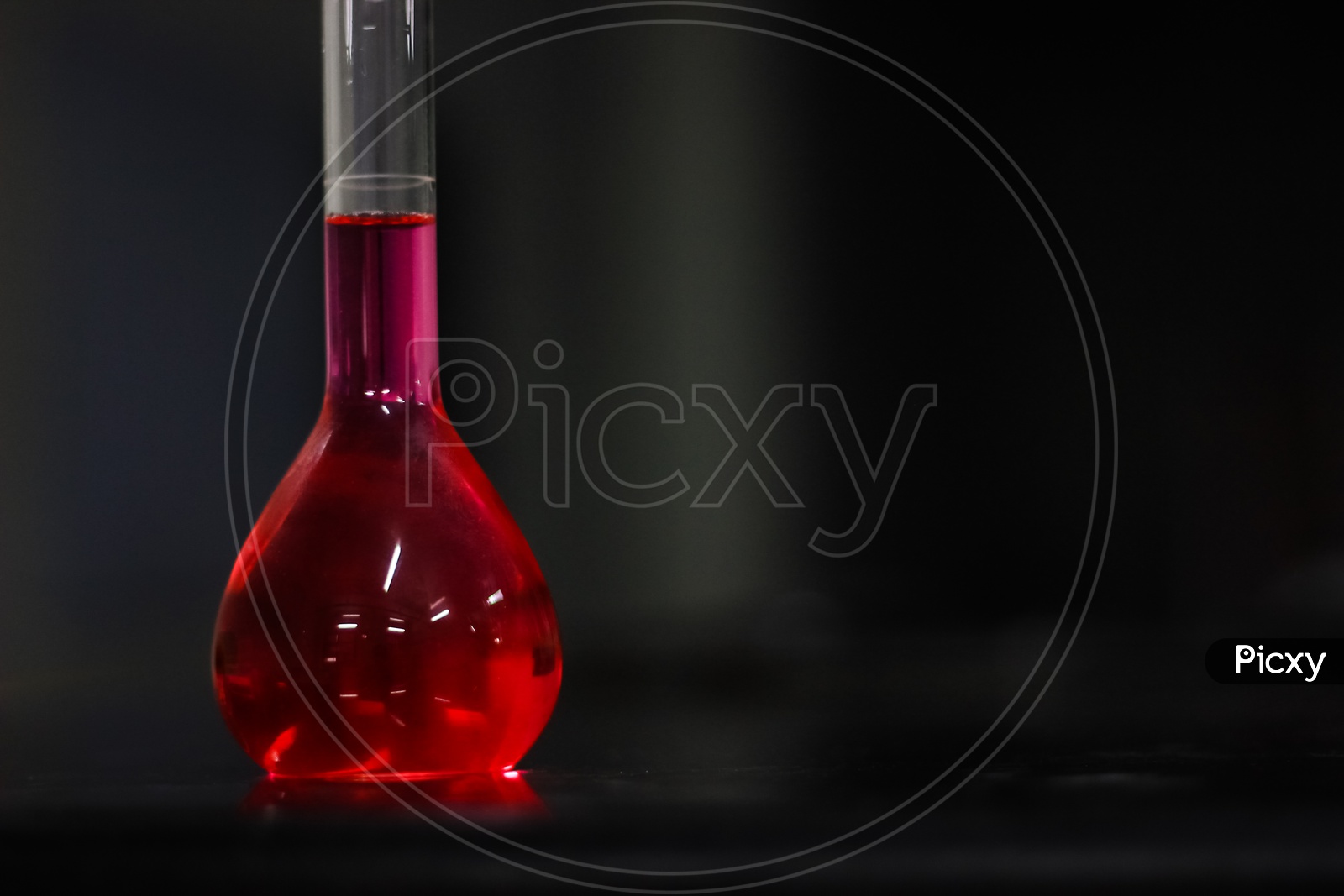 Red Liquid In A Round Bottomed Flask On A Black Granite Table In Dark Background