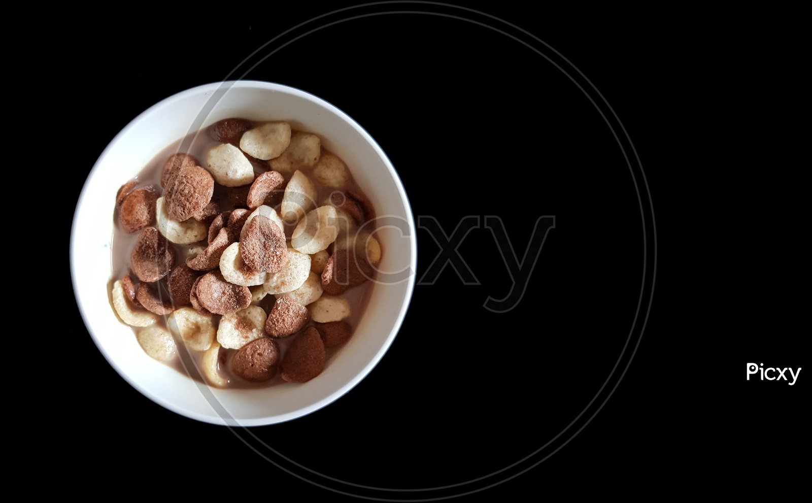 Vanilla And Chocolate Cornflakes Dipped In Chocolate Milk In A White Bowl In Black Background