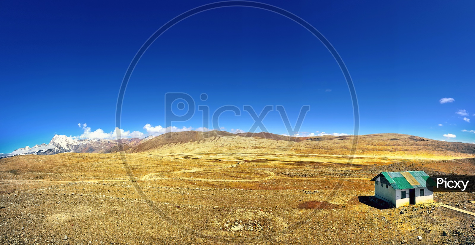 A House On A Deserted Land With Arid Soil And Blue Sky