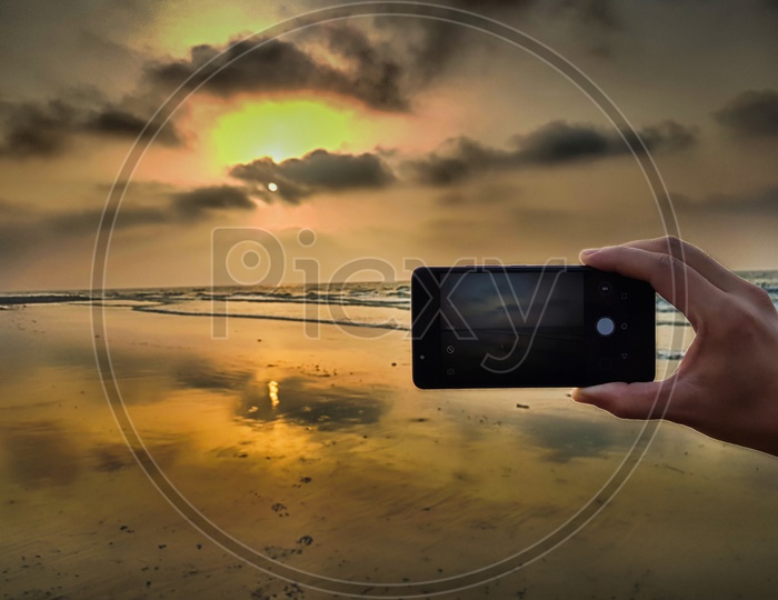 Hand Taking Photo Of A Beach Sunset With Smartphone