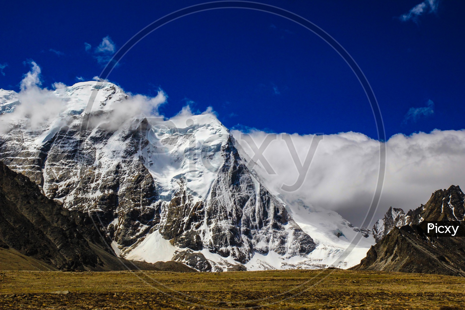 Landscape Of Deep Blue Sky And Ice Capped Peaks Of Himalayan Mountains With White Clouds During Day Time