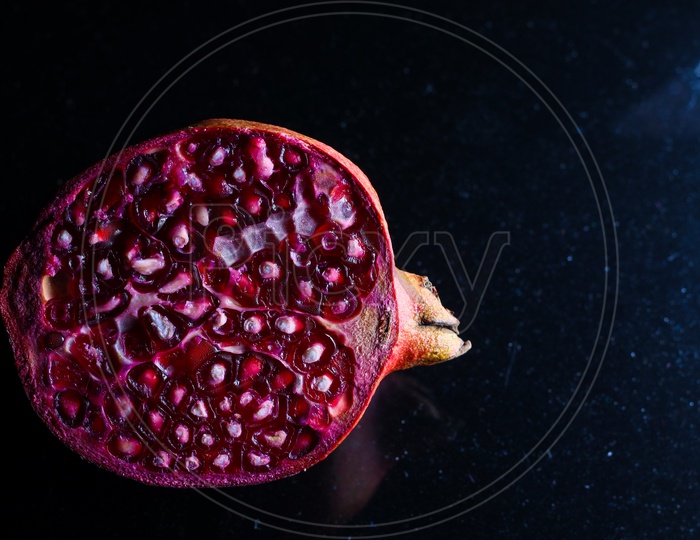 Close Up Photo Of Cut Pomegranate In Dark Background