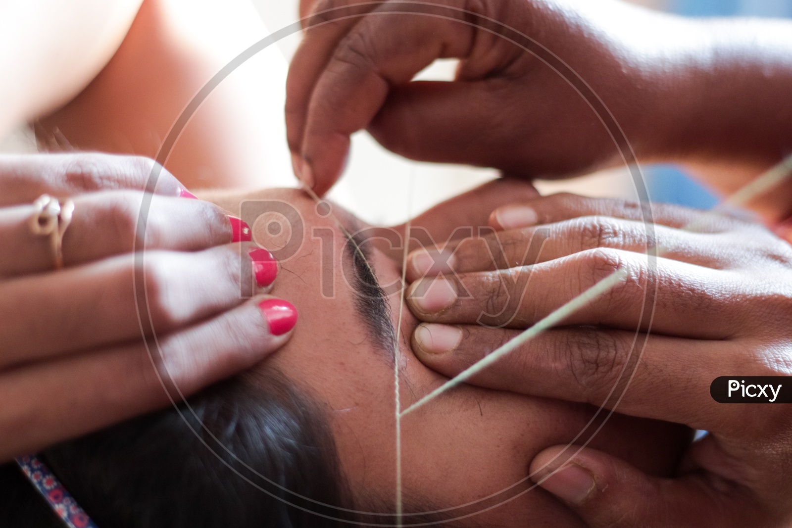 shaping and plucking of eye brow with threading. epilation cosmetic procedure in beauty parlour.