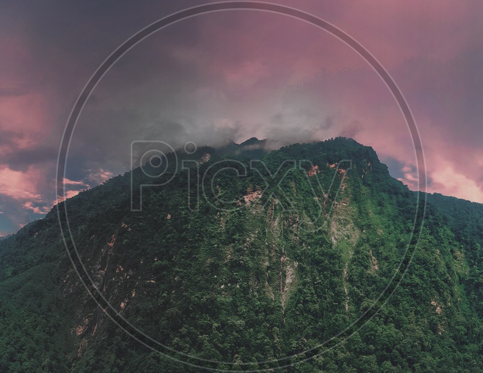 Red Sky With Fog On A Mountain Top With Green Vegetation