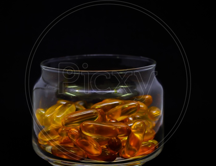 Cod Liver Oil Omega 3 Vitamin E Gel Capsules Isolated On Black Background In A Transparent Glass Bottle