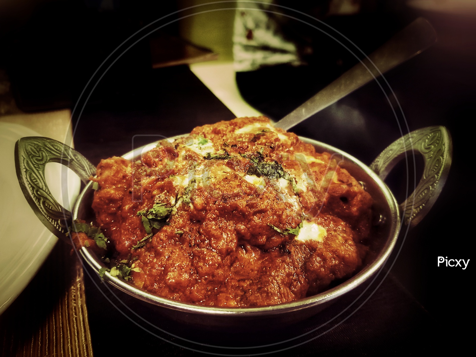 Chicken Tikka Masala In A Kadhai With Spoon With Butter And Coriender Leaf