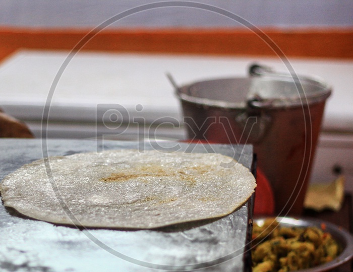 Freeing The Edge Of Paper Plain Dosa On A Tawa Pan By Cooking Spoon After The Dosa Is Fried In Oil.