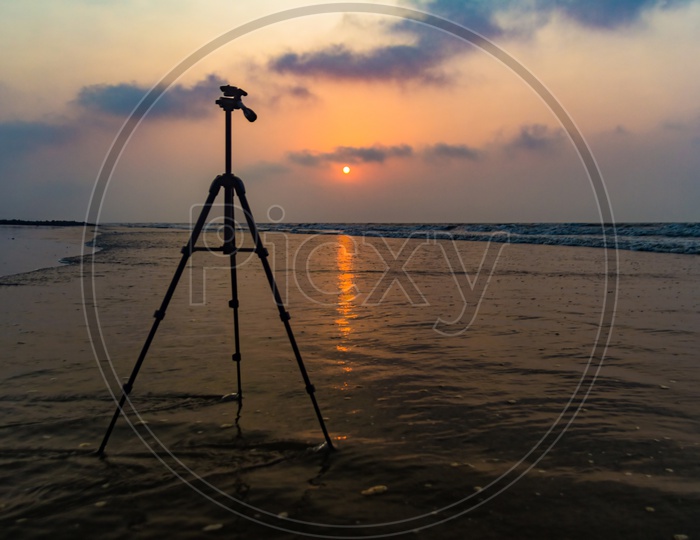 Tripod In Background Of Sunrise At Sea Beach For Beach Photography With Space For Text