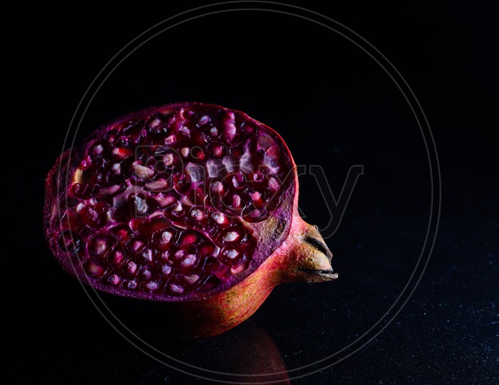 Close Up Photo Of Cut Pomegranate In Dark Background