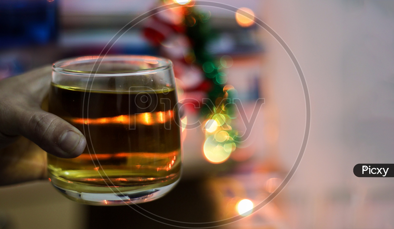 A Glass Of Alcohol Whisky Held In Hand With Background Blur Bokeh Lights
