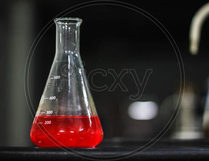 Red Liquid In A Glass Conical Flask On A Black Granite Table In Dark Background