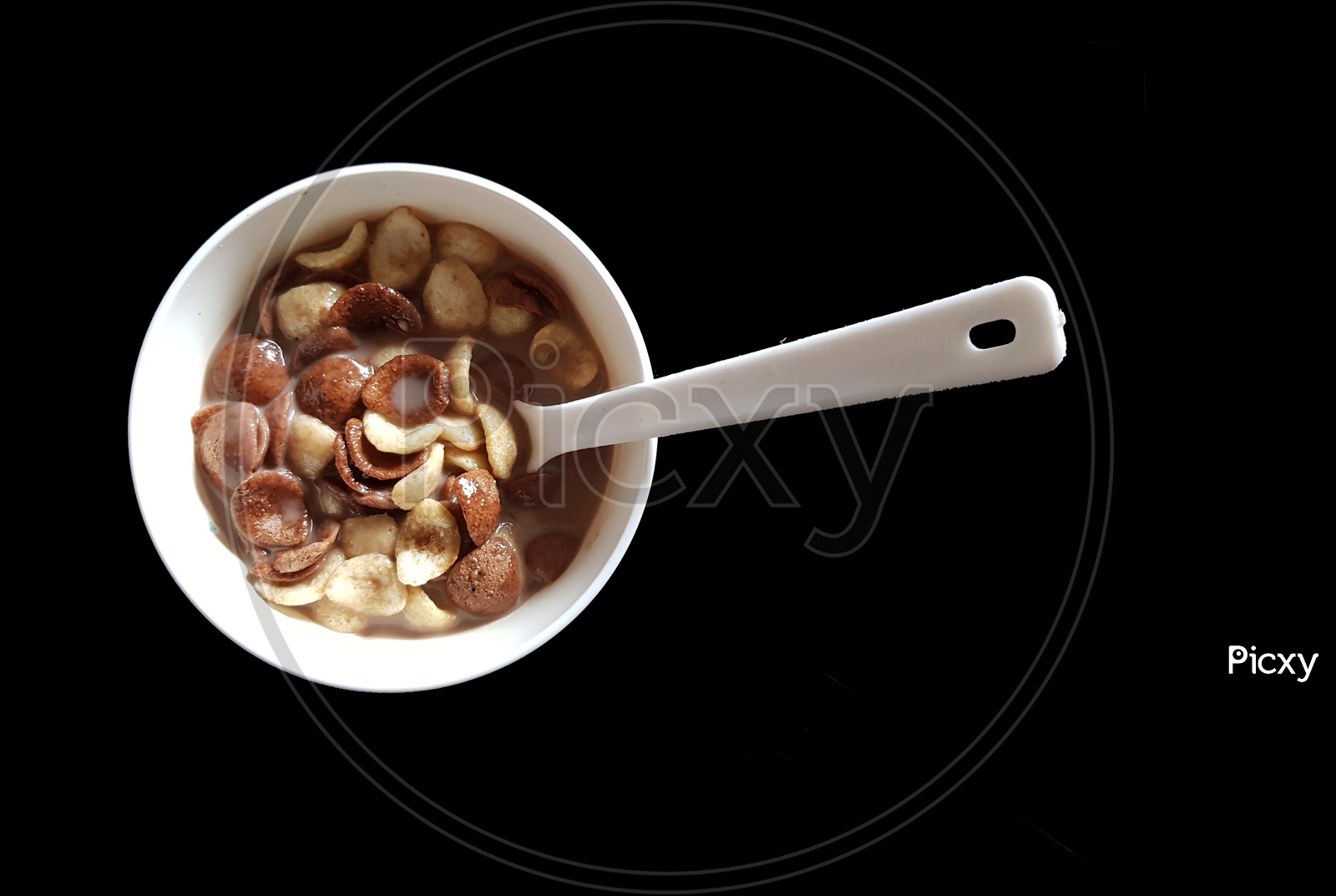 Vanilla And Chocolate Cornflakes Dipped In Chocolate Milk In A White Bowl With Spoon In Black Background