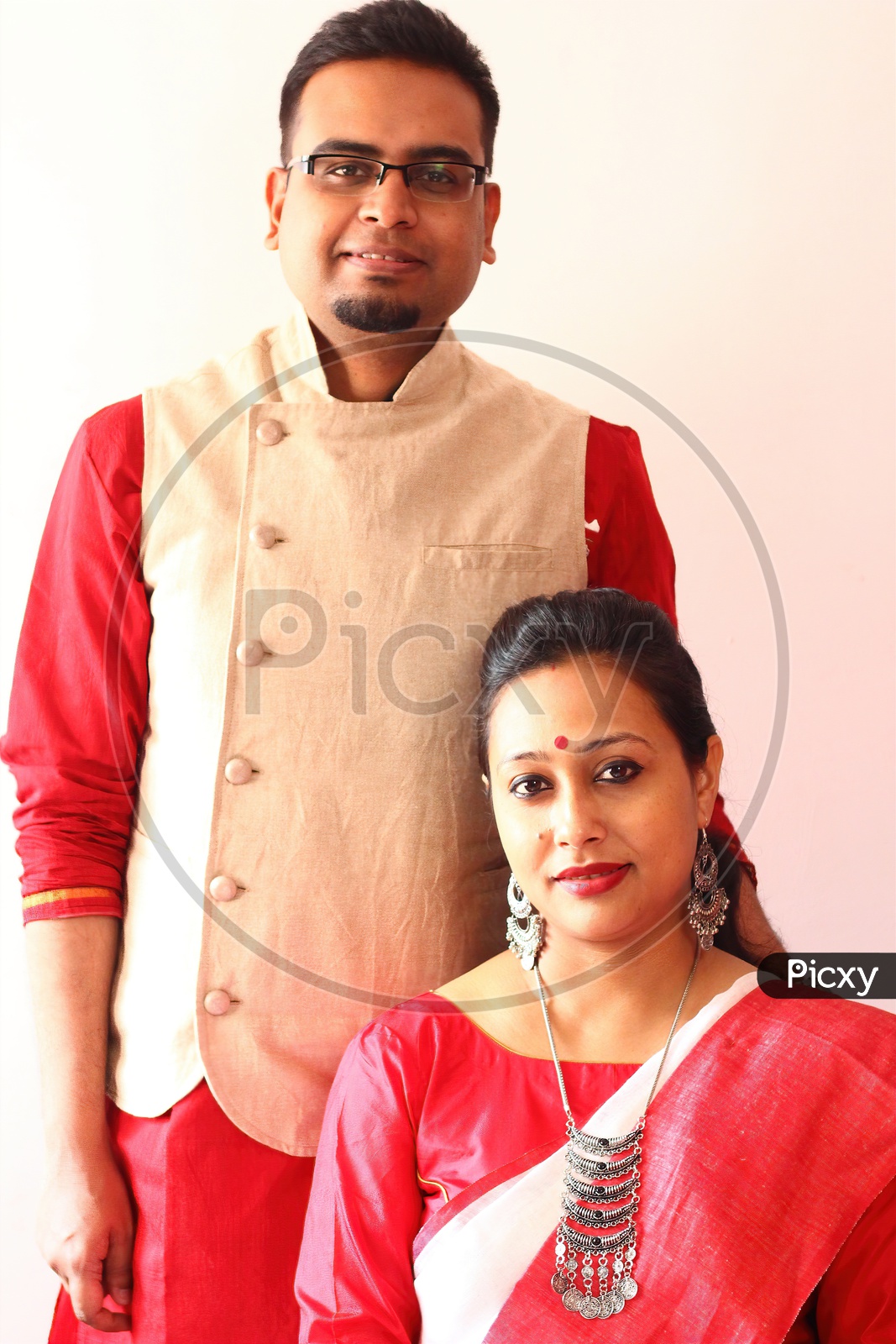 A Young Indian Bengali Assamese Married Couple Dressed In Red And White Ethnic Indian Dress