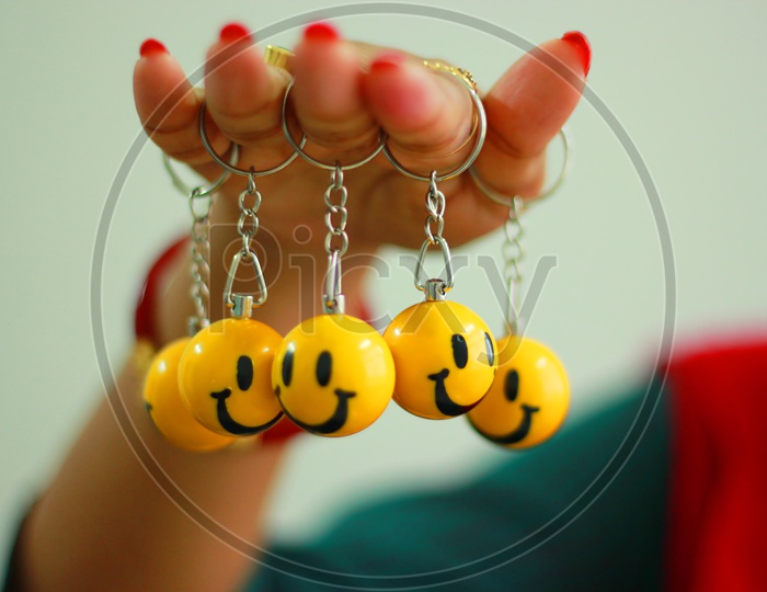 Smiley Key Rings Hanging From Fingers Of A Lady, Symbol Of Joy
