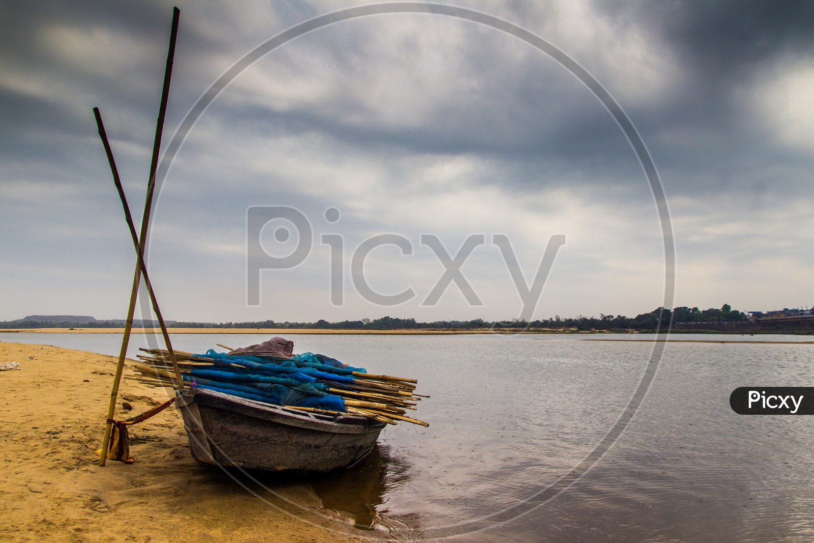 Landscape Of A Boar Tied At The Corner Of River Bed Sandy Beach And Cloudy Sky Day Time Scene.