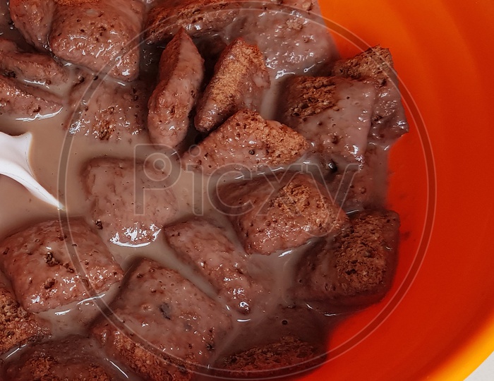 Close Up Photo Of Chocolate Cornflakes Dipped In Chocolate Milk In With Spoon