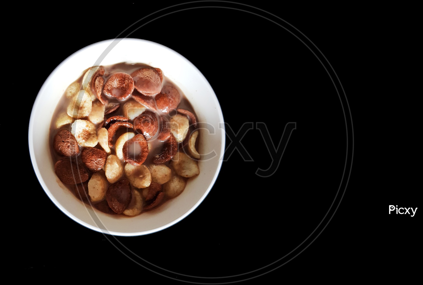 Vanilla And Chocolate Cornflakes Dipped In Chocolate Milk In A White Bowl In Black Background