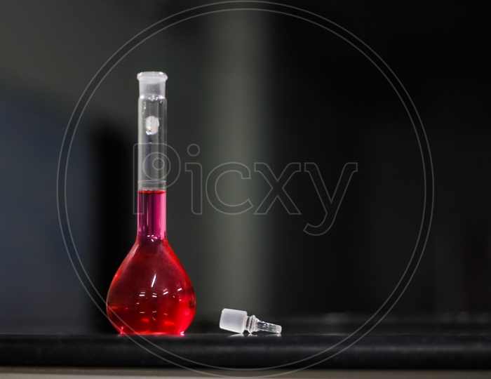 Red Liquid In A Round Bottomed Flask On A Black Granite Table In Dark Background