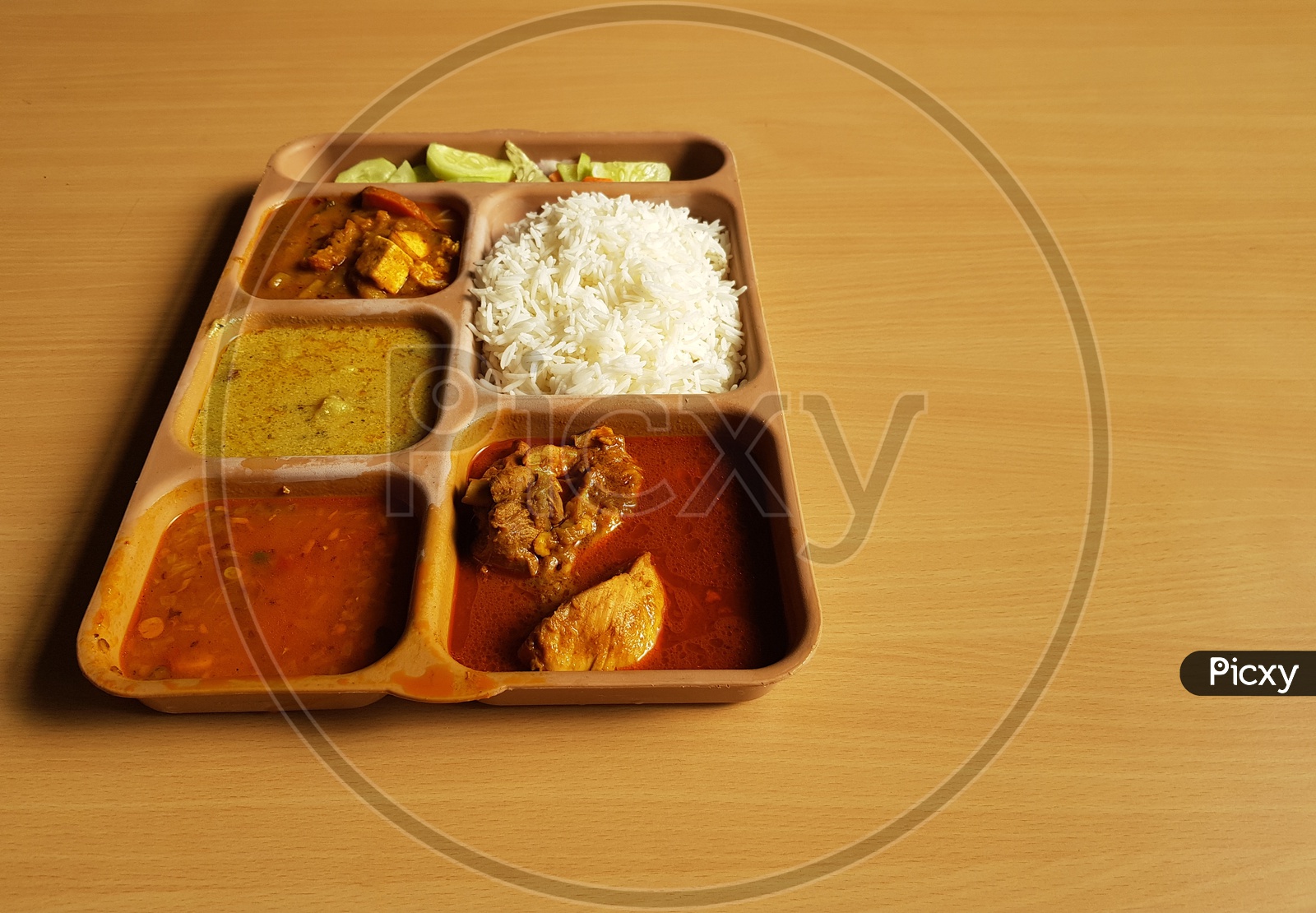 Indian Chicken Thali With Rice Dal Chicken Salad Vegetable Curry On A Plastic Segmented Plate In Wooden Background
