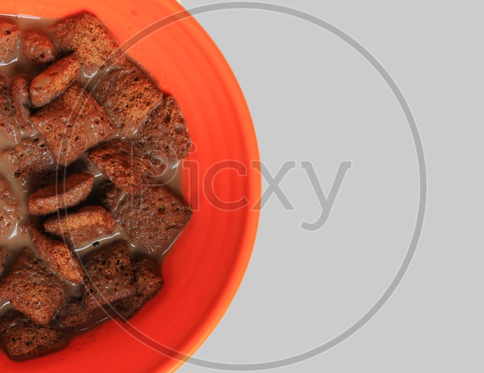 Chocolate Filled Cookies Dipped In Chocolate Milk On An Orange Bowl In Light Background