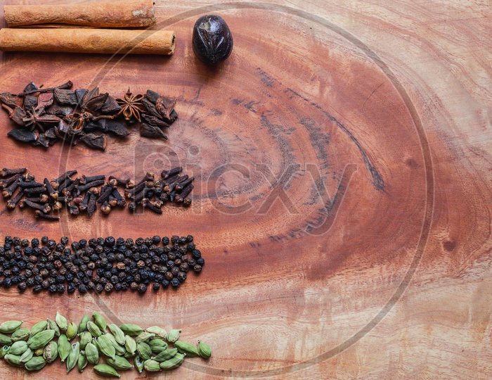 Typical Ingredients For A Garam Masala Black Peppercorns, Mace, Cinnamon, Cloves, And Green Cardamom In A Wooden Background