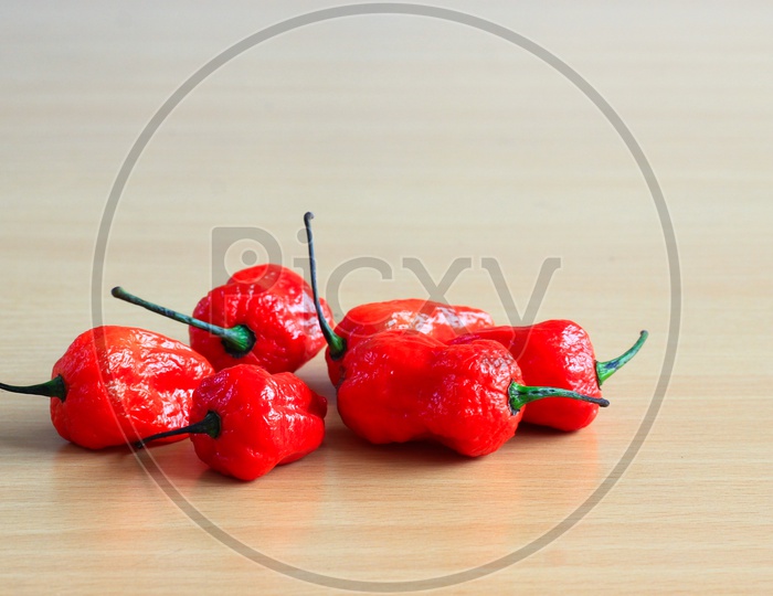 Bunch Of Red Bhoot Jolokia Spicy Ghost Pepper Isolated In Wooden Background With Space For Text