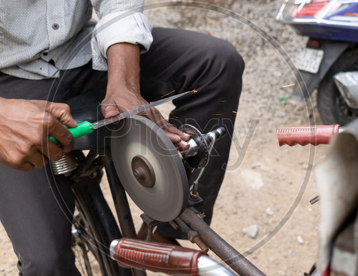 Man Sharpening Knife With Grinder Roll Rod  On Bicycle