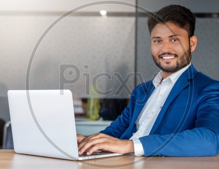 Happy Indian Businessman Working On Laptop With Smile Face In Indoor