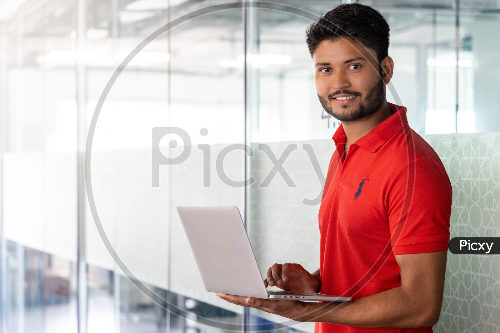 Indian Male Student Holding  a Laptop With Indoor Backdrop
