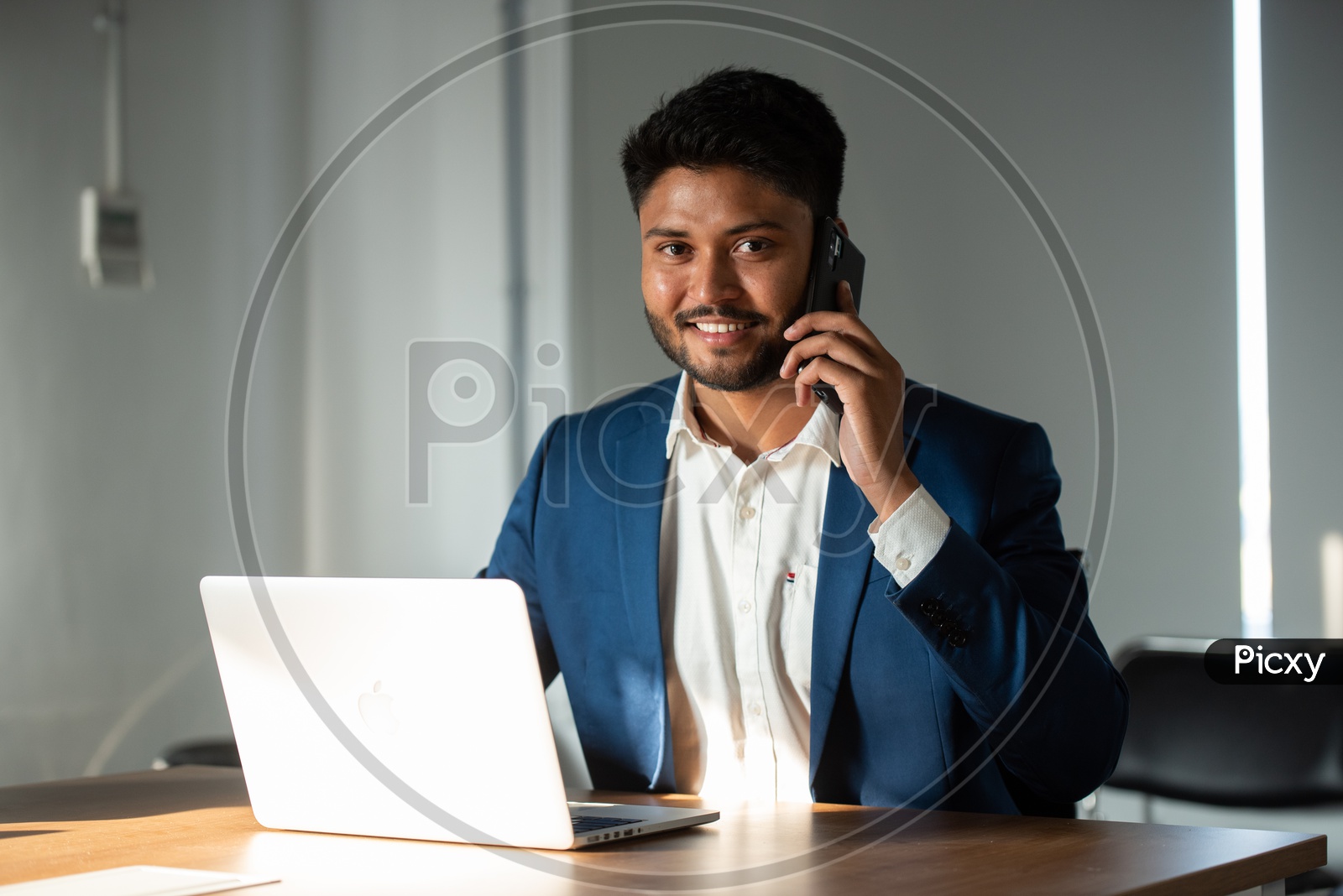Indian Businessman Speaking In Smartphone At Office Work space Background